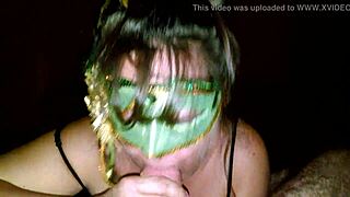 A mature woman with a green mask gives a deep throat to a large penis