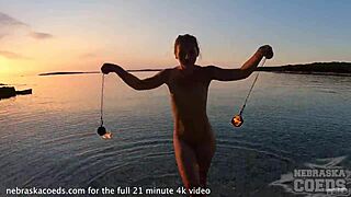 Sultry European beauty performs mesmerizing fire dance on nude beach at sunset