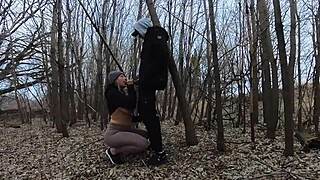 A blonde wife gives a blow job to her husband in a park.