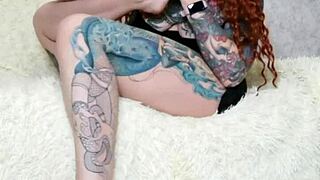 Beautiful tattooed woman in a dress and socks has foot fetish