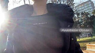 A beautiful woman exposes her large breasts while walking in a public park