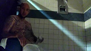 A man with a tattooed body and a large penis masturbates in the webcam